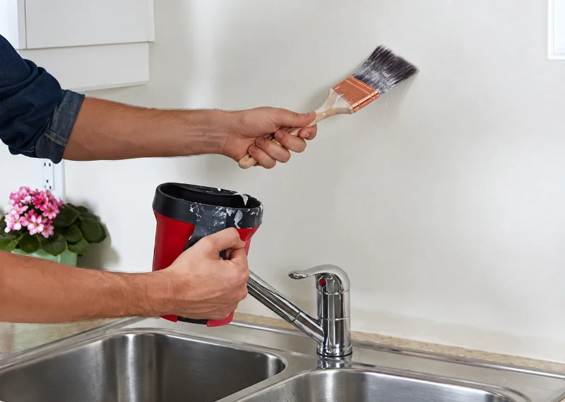 Travaux de peinture dans une cuisine, au-dessus d’un évier